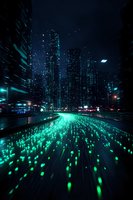 Futuristic cityscape at night with glowing green light trails leading to illuminated skyscrapers, creating dynamic motion effect against dark urban backdrop.
