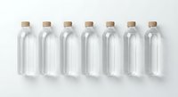 Seven clear glass bottles with cork stoppers arranged in row on white background for packaging design and branding projects.