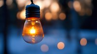 Glowing light bulb with warm illumination against blurred bokeh background at dusk creates atmospheric mood for creative and inspirational concepts.