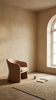 Minimalist interior with beige upholstered armchair, arched window, natural light, wooden floor, and neutral textured walls. Suitable for home decor, interior design, and lifestyle publications.