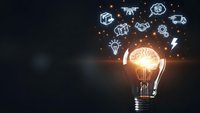 Glowing light bulb with brain inside surrounded by floating business icons representing innovation, creativity and entrepreneurship concepts.