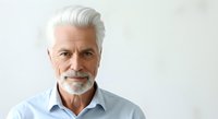 Senior man with white hair and beard wearing light blue shirt, isolated on white background for corporate, business, and professional portrait use.