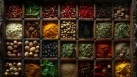 Aromatic spices and herbs in wooden box compartments, colorful cooking ingredients including peppercorns, nutmeg, turmeric powder, and dried herbs arranged in rustic display.