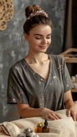 Young Caucasian woman with messy bun hairstyle wearing floral print top smiling while working with natural textiles in cozy craft workspace setting.