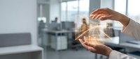 Professional hands protecting glowing city skyline hologram in modern office environment representing urban development and real estate investment security.