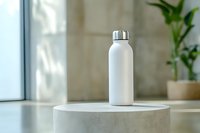 White reusable stainless steel water bottle on concrete pedestal near window with natural light and houseplant, eco-friendly sustainable lifestyle concept.