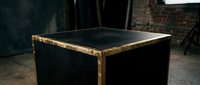 Vintage black wooden table with golden brass metal edges in rustic industrial interior setting for furniture design and home decor projects.