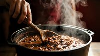 Chef stirring hot stew in pot with steam rising, suitable for cooking, food preparation, culinary education and restaurant marketing materials.