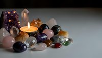 Collection of healing crystals and gemstones with burning candle for meditation, spiritual wellness, alternative therapy and energy healing practices.