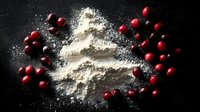 Fresh cranberries scattered around white flour on dark slate surface for holiday baking and cooking projects.