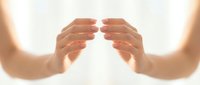 Two hands reaching toward each other in protective gesture against bright white background symbolizing connection, support and unity in healthcare concept.