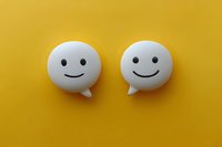 White speech bubble emoticons with happy smiling faces on vibrant yellow background, representing positive communication and friendly dialogue.