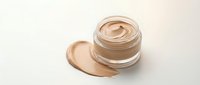 Open jar of beige foundation cream with smooth swirl texture and makeup smear on neutral background for cosmetic and beauty product design.