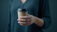 Woman in dark green sweater holding disposable coffee cup with black lid against moody teal background, minimalist lifestyle concept for coffee break.