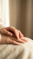 Soft close-up of female hands resting gently on a cozy knit fabric, conveying calm, mindfulness, and self-care in warm neutral tones.