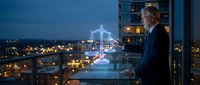 Senior Caucasian businessman in suit holding glowing digital justice scales hologram at night office window overlooking city lights for legal technology concepts.