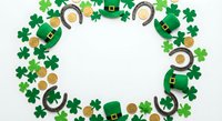 St. Patrick's Day festive frame with green shamrocks, leprechaun hats, horseshoes and gold coins on white background for holiday greeting cards and decorations.