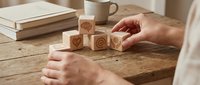 Person arranging wooden blocks with contact icons on rustic desk for business communication and customer service concepts.