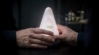 Hands gently protecting glowing pyramid light source in dark environment symbolizing guidance, protection, innovation and spiritual enlightenment concept.