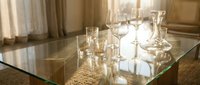 Elegant glassware and crystal stemware arranged on reflective table surface with warm natural lighting, suitable for fine dining, event planning, hospitality, and luxury lifestyle content.