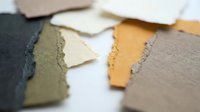 Colorful torn paper pieces in earth tones scattered on white surface for creative collage and scrapbooking projects.