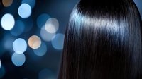 Silky smooth straight dark hair on blurred bokeh background in blue tones. Professional hairstyle and haircare concept showing healthy, glossy brunette hair strands.