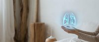 Woman holding glowing holographic lungs projection in modern interior. Healthcare technology concept for medical presentations and respiratory health awareness.