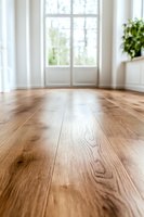 Hardwood oak flooring in bright modern room with french doors and natural light. Low angle view shows wood grain texture and warm tones for interior design.