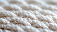 Extreme close up macro shot of natural cotton fabric texture showing white fibers and threads in soft beige tones, suitable for textile industry backgrounds.