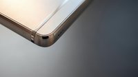 Modern smartphone corner detail showing rose gold metallic frame and glass surface on gradient background for technology and mobile device concepts.