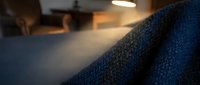 Cozy blue knitted sweater texture in warm home interior with soft lighting and blurred background creating comfortable atmosphere for relaxation.
