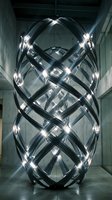 Futuristic metallic sculpture with glowing lights in modern concrete interior space for contemporary art and design projects.