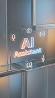 Futuristic transparent glass interface displaying glowing AI Assistant text with digital icons for voice, camera, and music controls in modern tech environment.