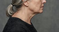 Senior woman in profile showing natural aging process with gray hair and wrinkles against neutral background for healthcare and wellness concepts.