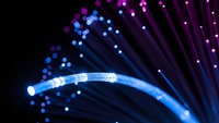 Fiber optic cables with glowing blue and purple light effects creating dynamic streaks and bokeh patterns on dark background for technology concepts.