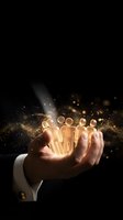 Businessman hand holding glowing golden team icons with magical light effects and sparkles on dark background for leadership and teamwork concepts.