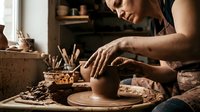 Professional potter shaping clay on spinning wheel in artisan workshop. Skilled craftsman creating handmade ceramic pottery with traditional techniques and tools.