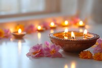 Glowing candles in decorative clay bowl with pink plumeria and marigold flowers creating serene spa atmosphere on white surface with soft bokeh light effect.