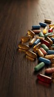 Colorful medicine capsules and pills scattered on dark wooden surface for healthcare and pharmaceutical industry concepts.