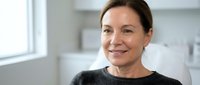 Professional middle-aged Caucasian businesswoman smiling confidently in modern office environment, corporate executive portrait for business presentations.