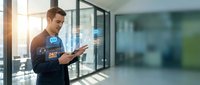 Caucasian male professional in business casual attire interacting with digital holographic interface in modern office environment with glass partitions and natural light.