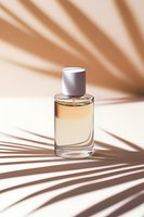 Elegant perfume bottle with palm leaf shadows on beige background. Minimalist luxury cosmetic product photography with natural sunlight effects.