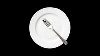 White ceramic dinner plate with silver fork, isolated on transparent background. Ready for restaurant menus, kitchen clipart, food blogs, t-shirt design, and print on demand use.
