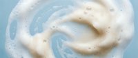 Creamy white foam swirl on a light blue background, showcasing soap lather texture for skincare, beauty, and cleaning product concepts.