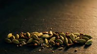 Roasted pistachio nuts scattered on dark surface with warm golden lighting, suitable for food photography, culinary content, and healthy snack marketing.