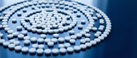 White pearl beads arranged in elegant spiral pattern on blue surface for jewelry making and craft projects.