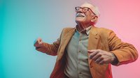 Senior Caucasian man in brown jacket and glasses dancing joyfully against colorful gradient background, expressing happiness and vitality in retirement years.