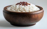 Steamed white rice topped with red pepper flakes in wooden bowl, ready for serving as side dish or base for Asian cuisine.