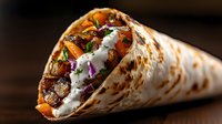 Grilled meat and vegetable wrap with creamy white sauce, fresh carrots, and purple onions in toasted tortilla on dark background. Perfect for menu design.