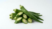 Fresh green okra pods with sliced pieces showing star-shaped cross-sections on white background. Healthy organic vegetable ingredient for cooking and nutrition.